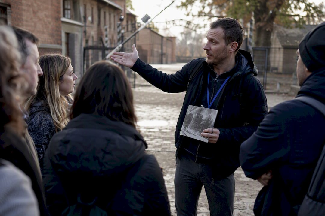 English guide explaining Auschwitz site to small group