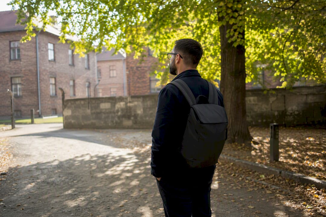 Visitor standing quietly at Auschwitz Memorial pathway