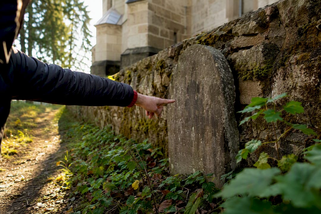 Hidden headstone behind a village church wall