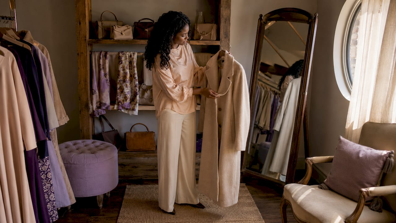 Woman examining wool coat in boutique fitting room light