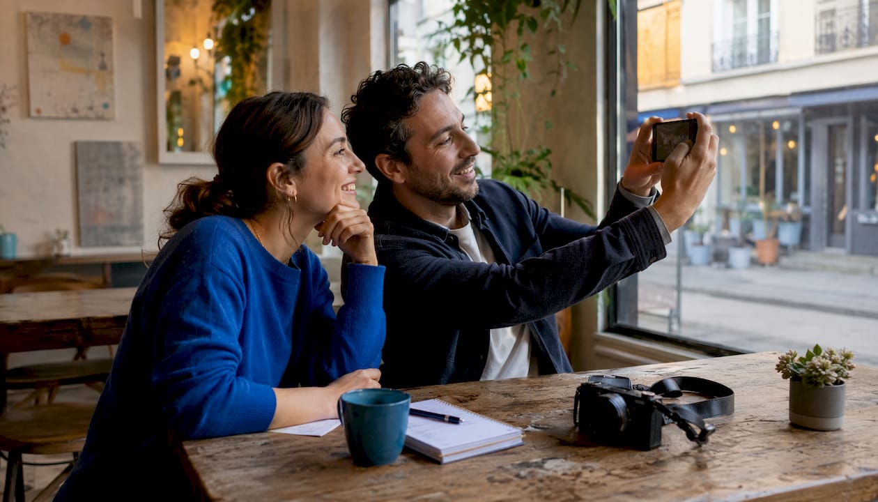 Eine Frau macht mit ihrem Smartphone ein Foto von der Schaufensterfront eines Geschäfts.