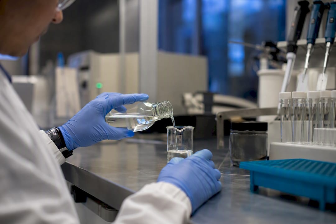 Technician pouring pharmaceutical solvent in QC lab