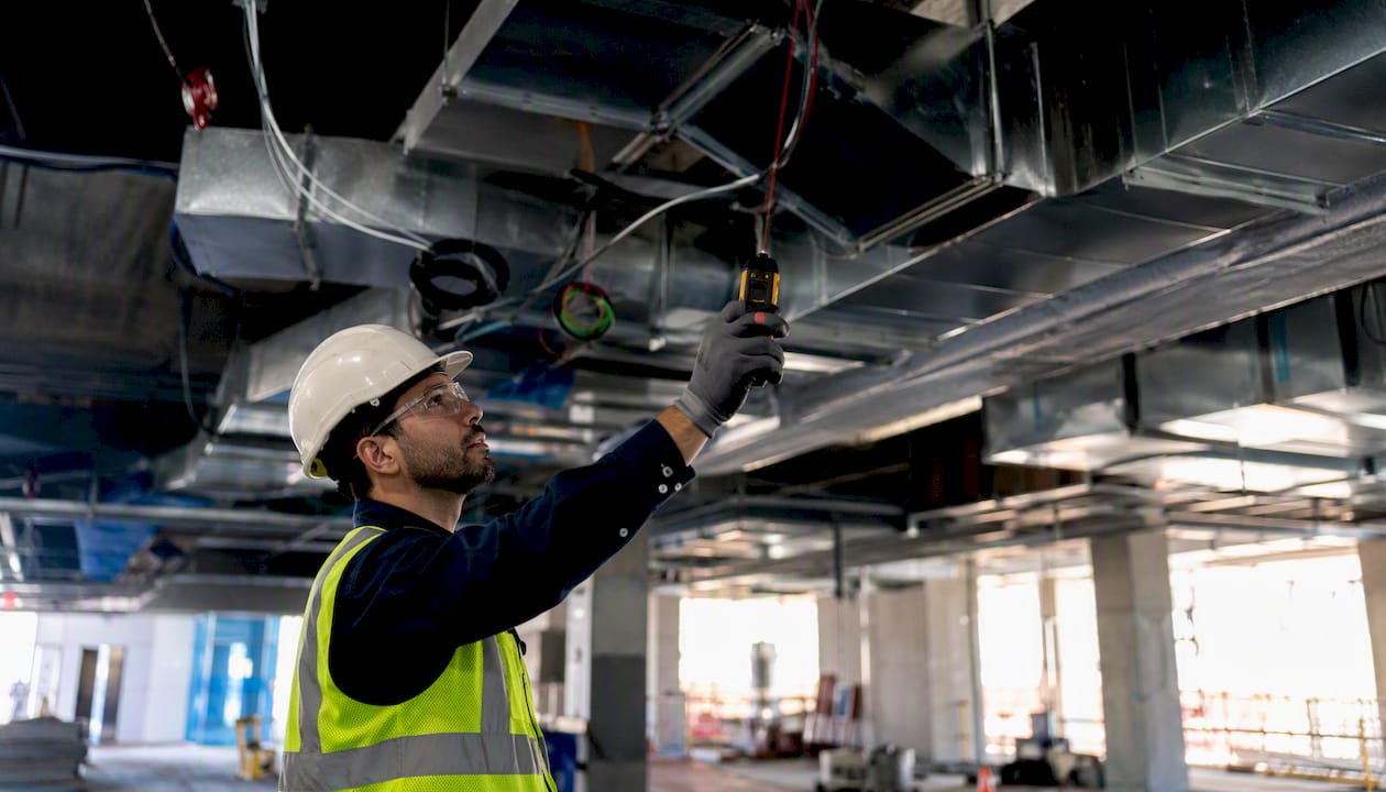 Hands measuring ductwork with laser meter