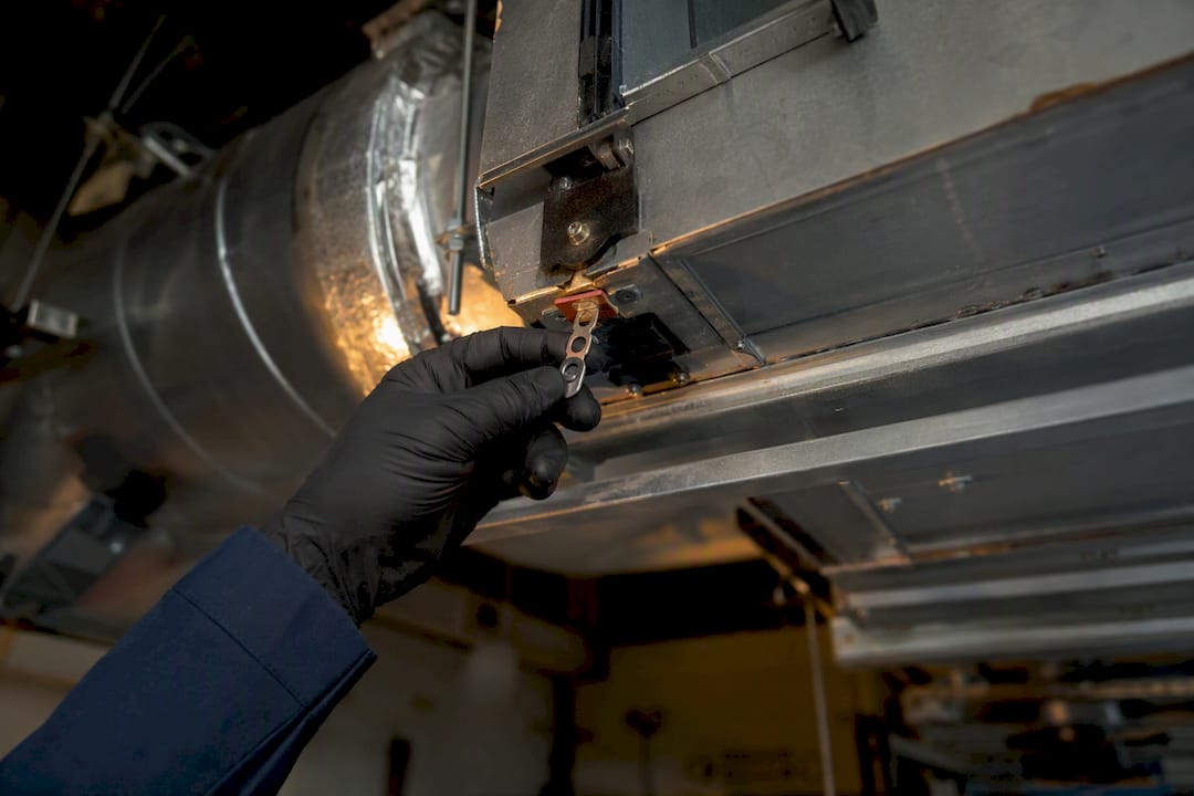 Technician inspecting fire damper fusible link