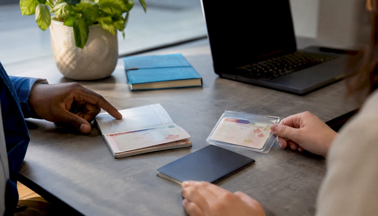 Hands holding different types of Canadian work permits