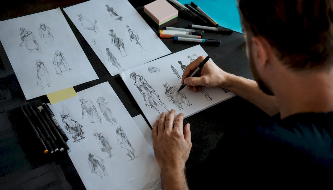 Designer drawing character silhouettes on desk