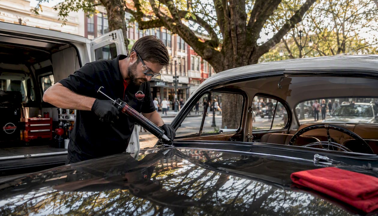 Technician replacing vintage car windshield outdoors