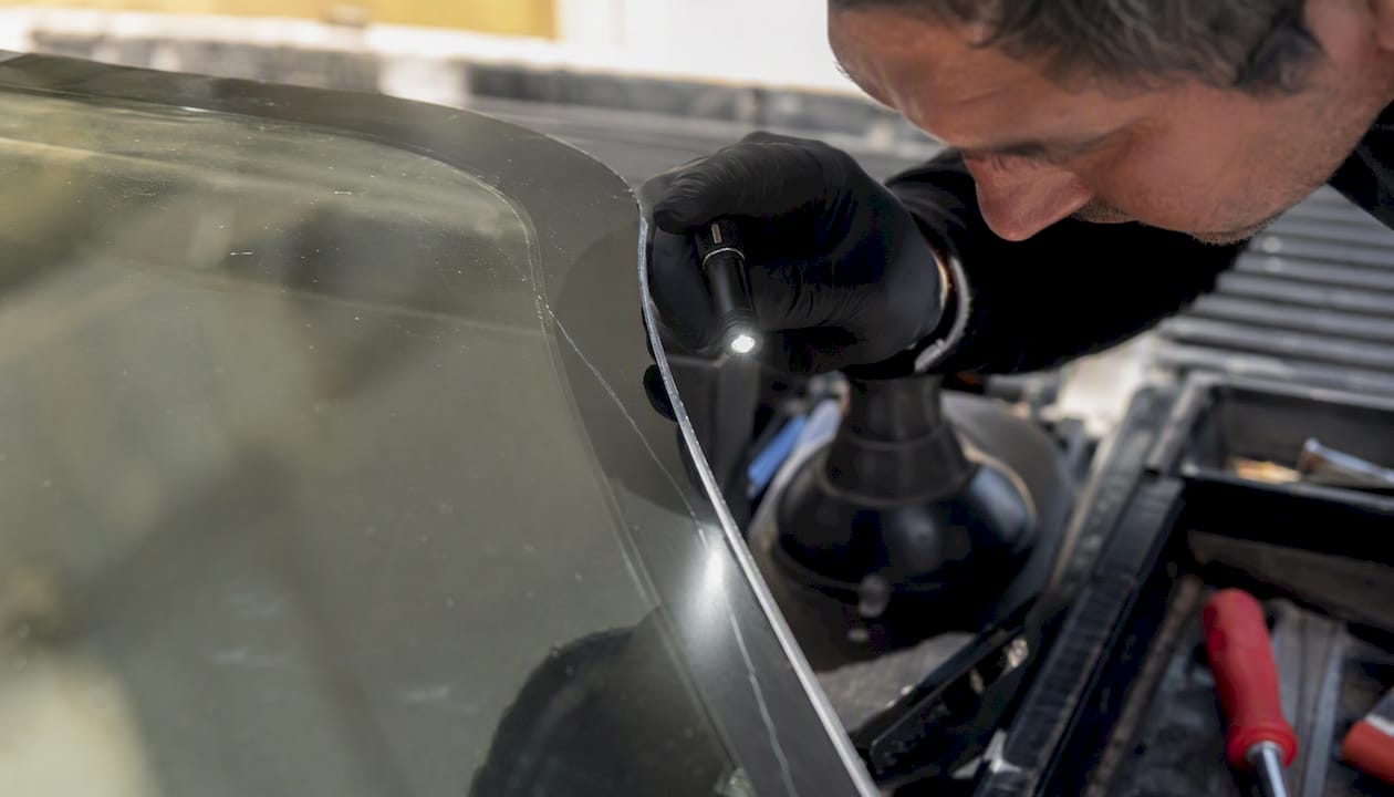 Technician inspecting windshield stress crack edge