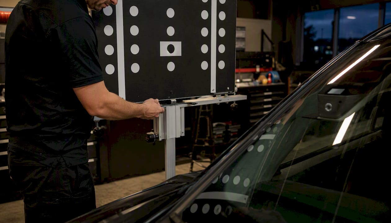 Technician calibrating ADAS camera on SUV windshield