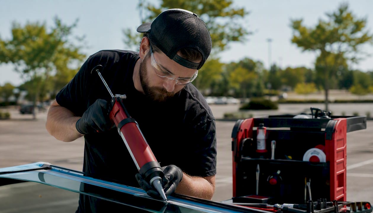 Technician applying urethane in outdoor mobile install