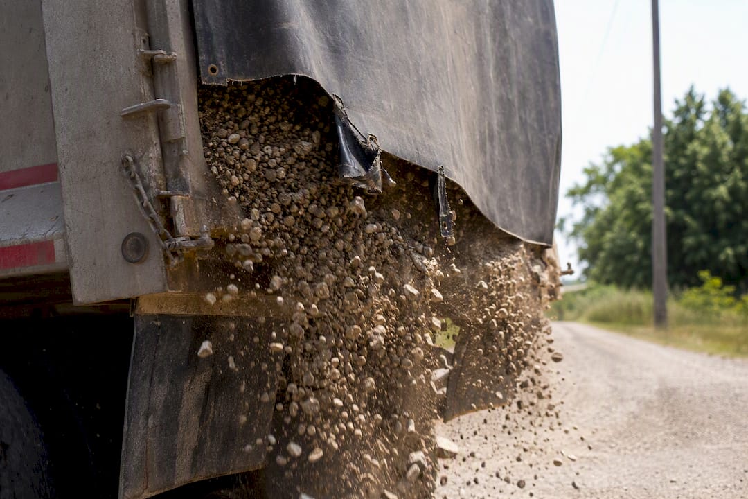 Loose gravel and torn tarp on a truck bed