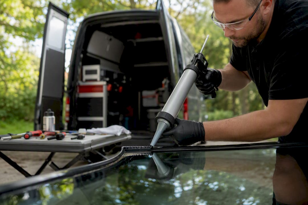Technician applying urethane adhesive bead on windshield frame