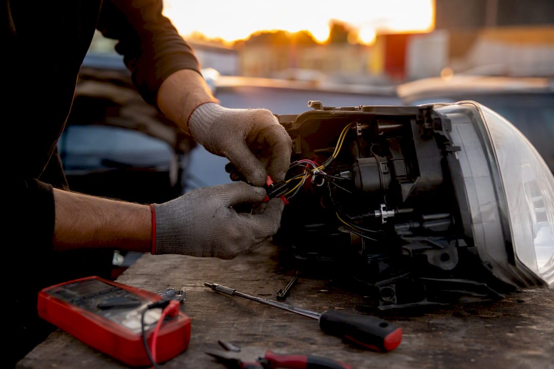 Technician inspecting vehicle headlight wiring