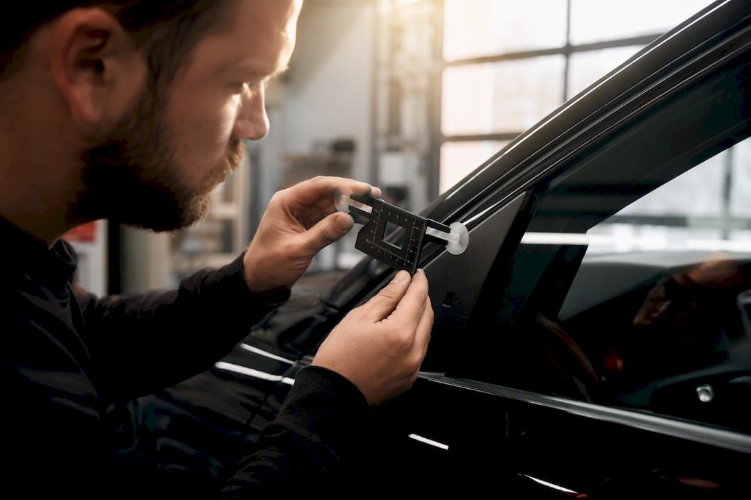 Technician inspecting side window for ADAS calibration
