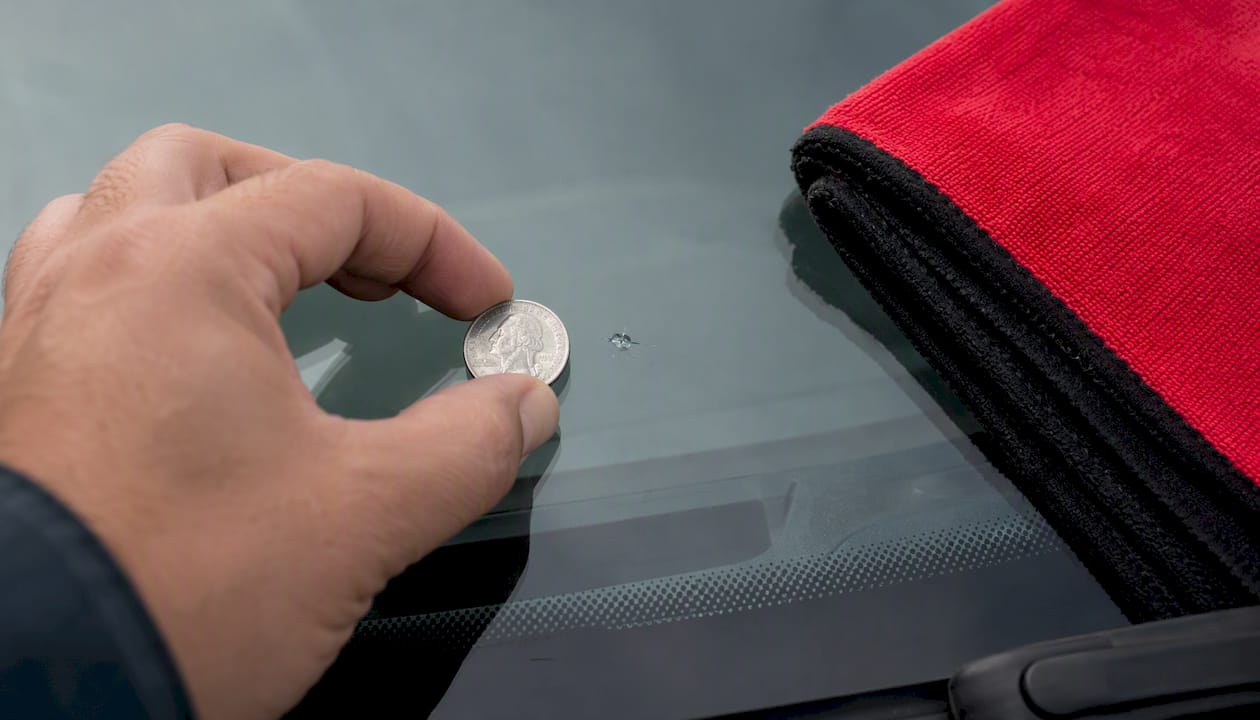 Coin beside small windshield chip for scale