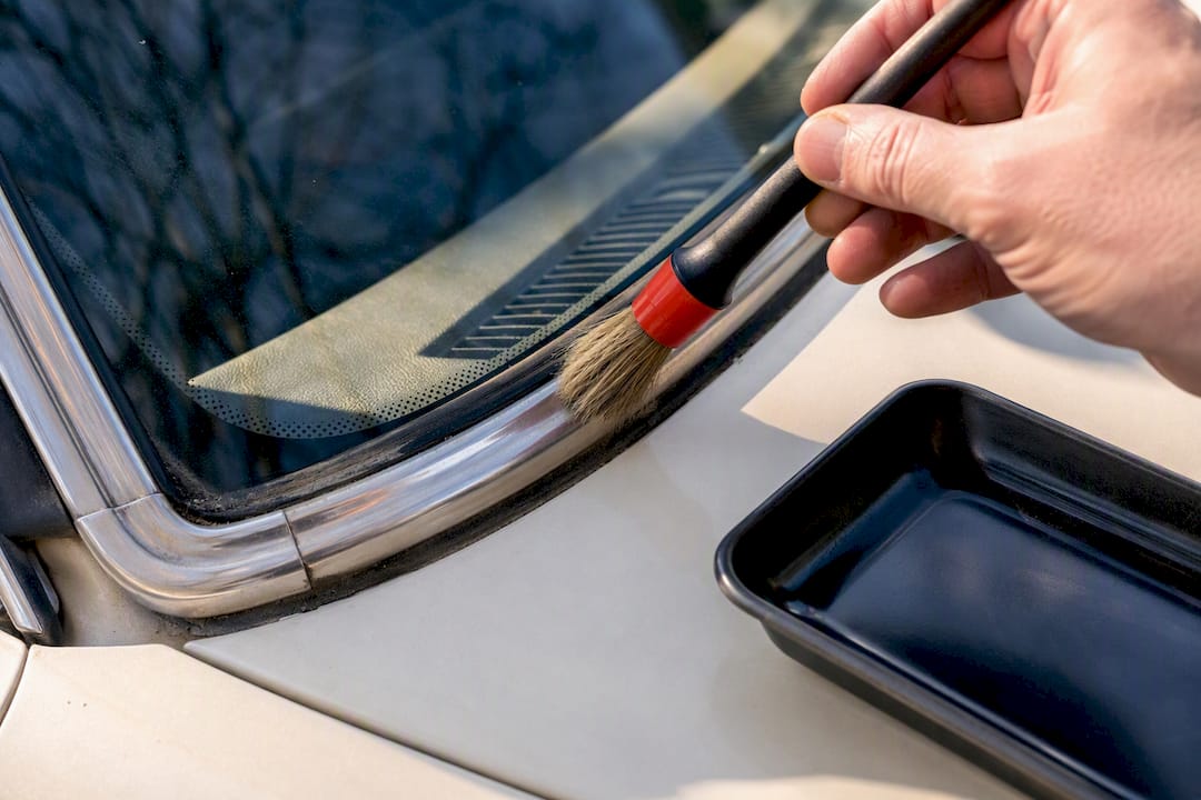 Brush cleaning grit from windshield trim channel