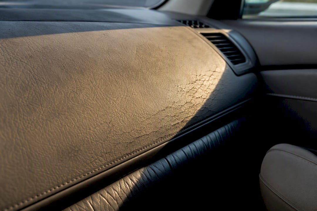 Sun-faded dashboard beside cracked leather trim