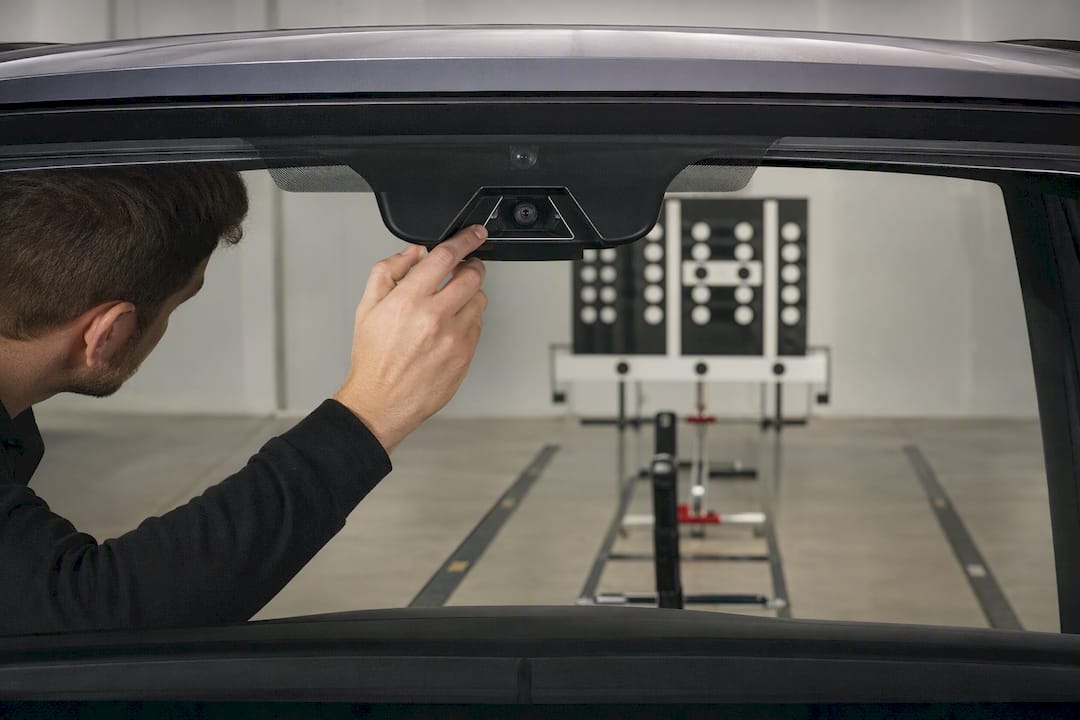 Technician aligning windshield camera calibration target