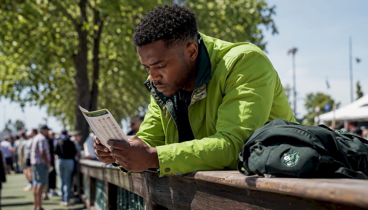 Man reviewing horse racing form outdoors at festival