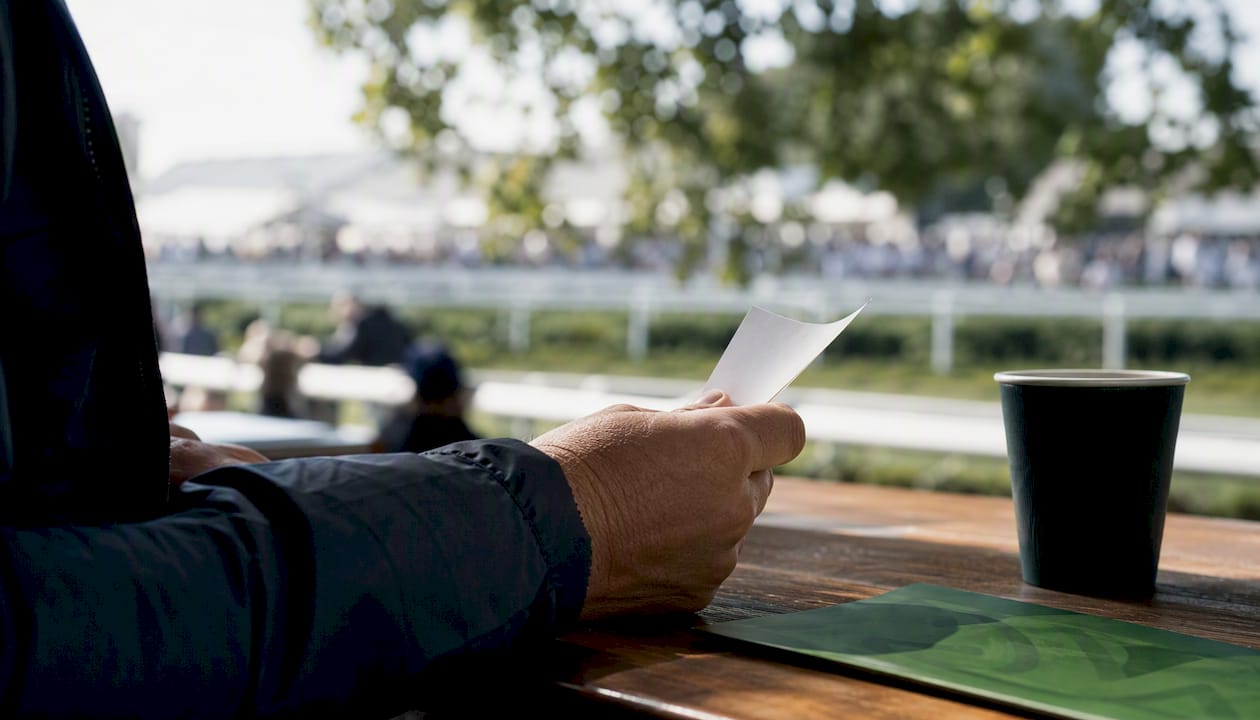 Hand holding betting slip near racetrack counter
