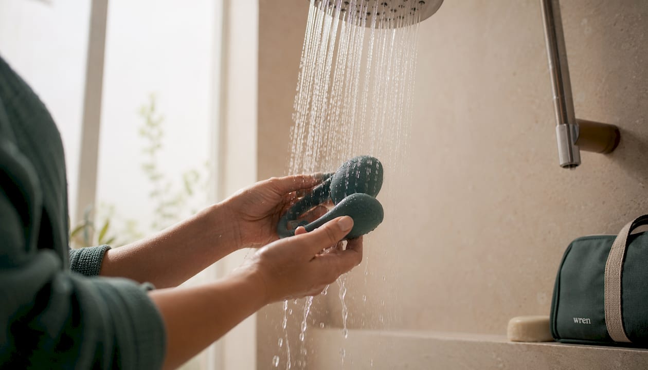 Hands rinsing heatless lactation massager under shower