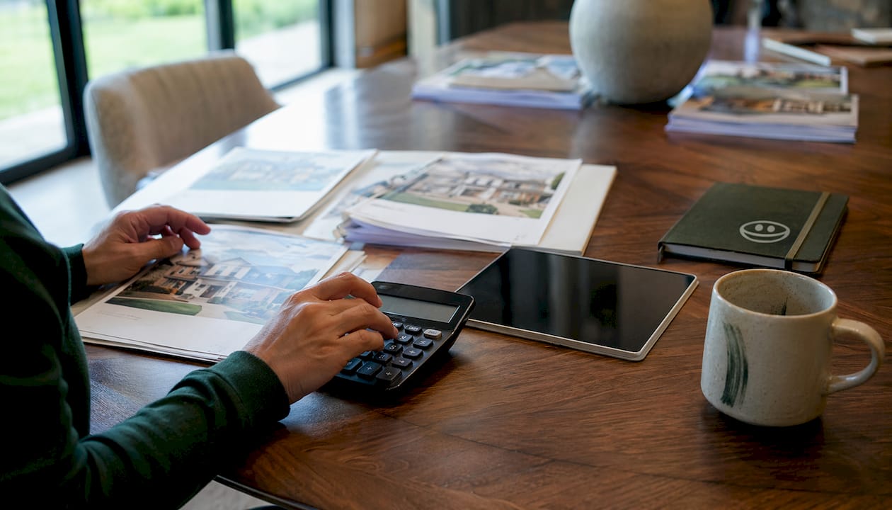 Hands calculating home price per square foot at kitchen counter