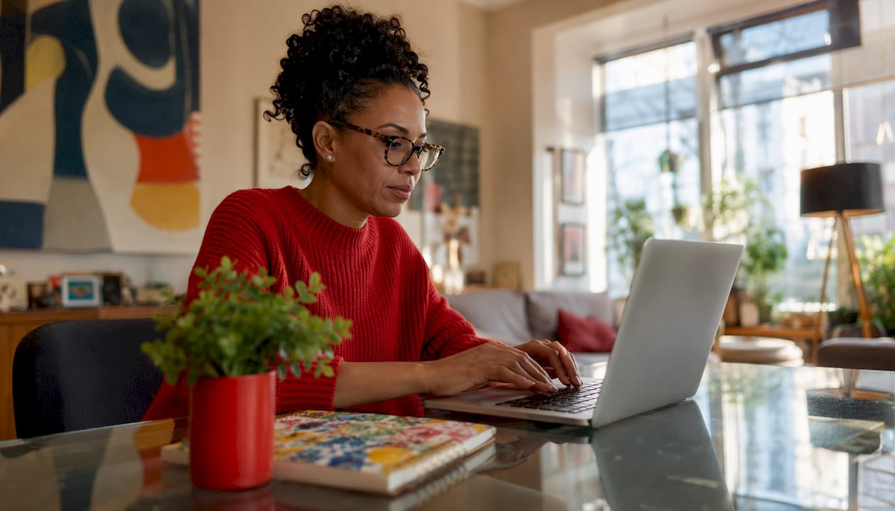 Content creator typing on laptop at home desk