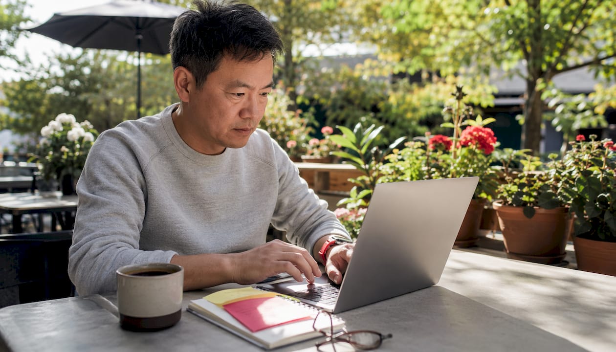 Man composing quote tweet on laptop in café