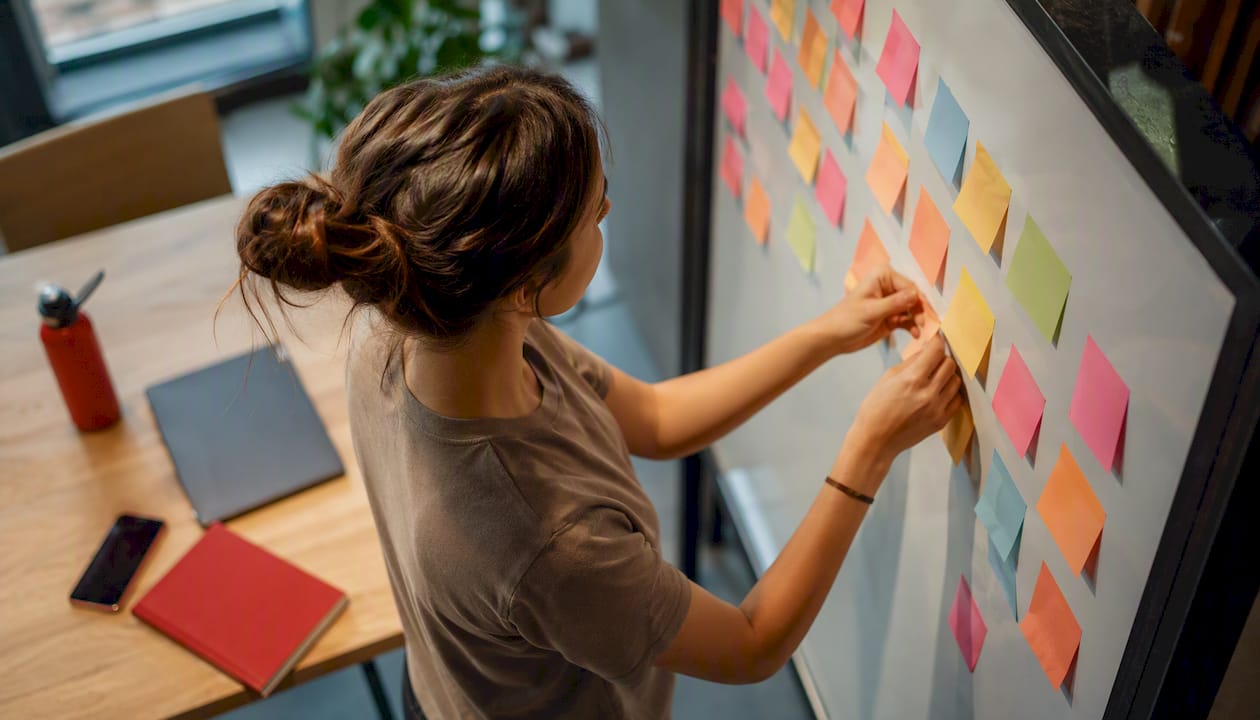 Hands arranging tweet-scheduling notes on board