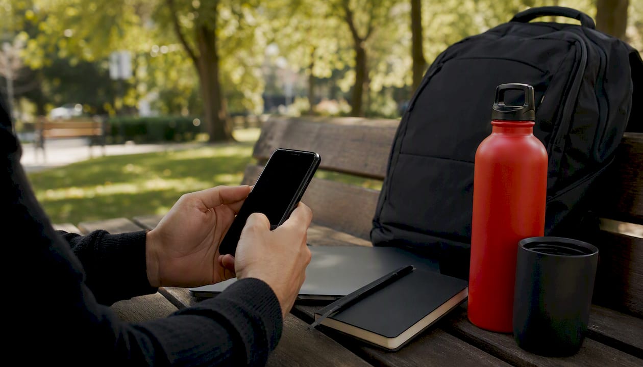 Hands dialing smartphone on dark desk