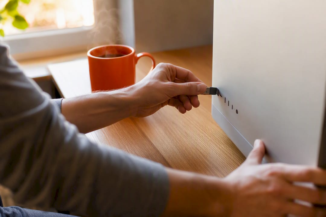 Hands unplugging USB flash drive from computer