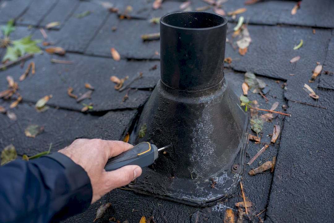 Hand checking roof vent boot condition after storm