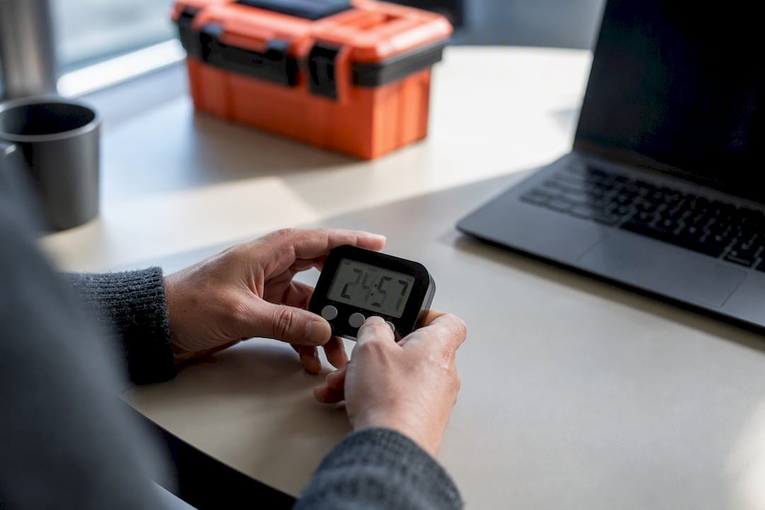 Gros plan sur des mains en train de régler un minuteur mécanique