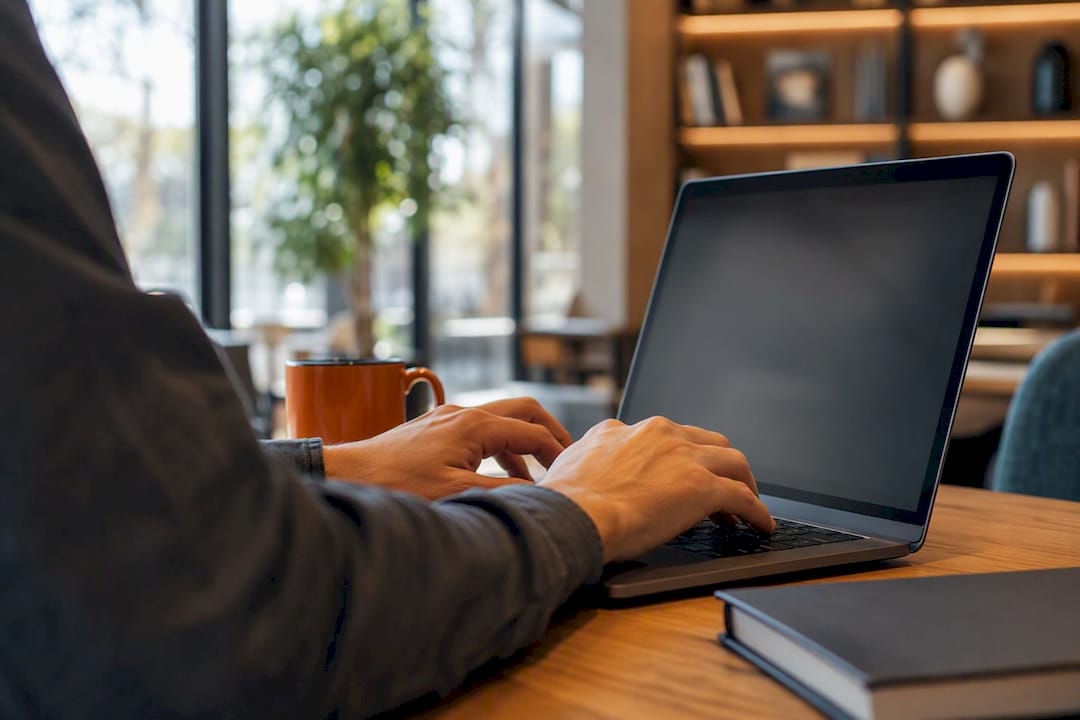 Des mains organisent des fichiers numériques sur le clavier d’un ordinateur portable.