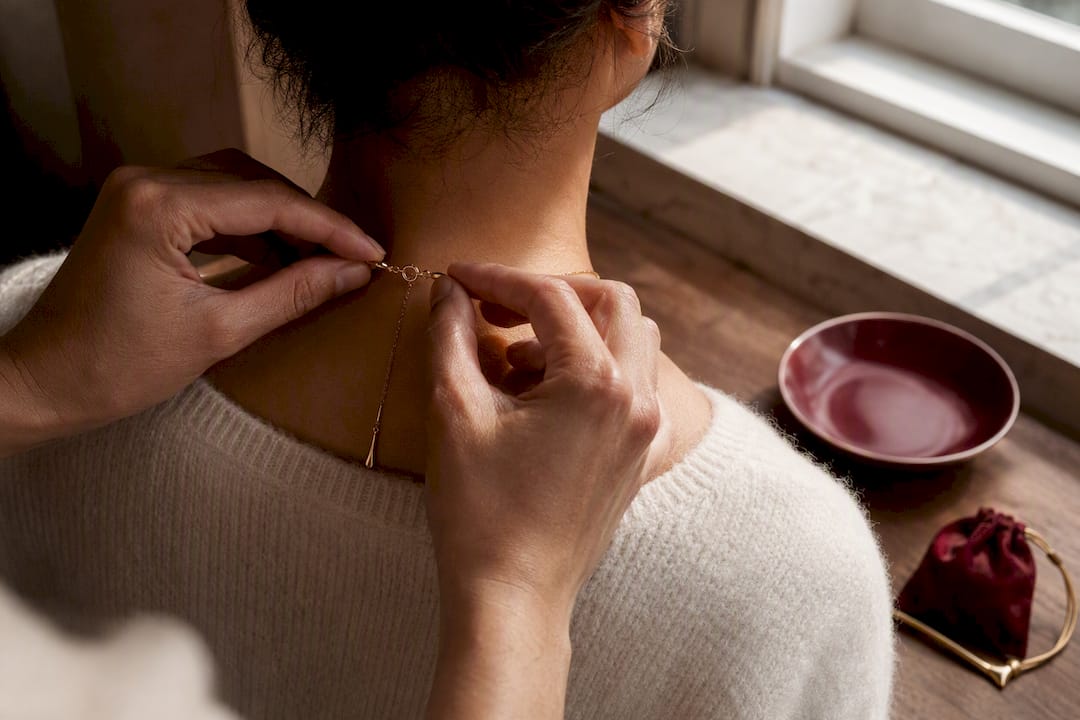 Hands fastening a discreet pendant necklace