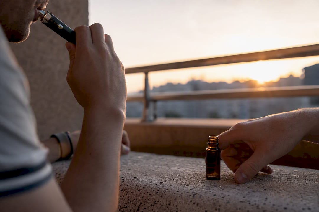 Hands using vape and tincture in routine