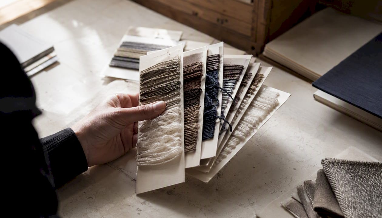 Hand holding yarn sample cards for colour testing