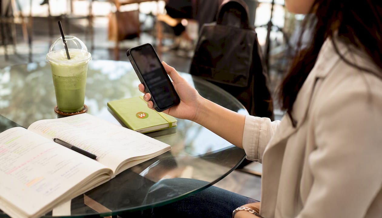 Hand using smartphone subtitle translation app in café