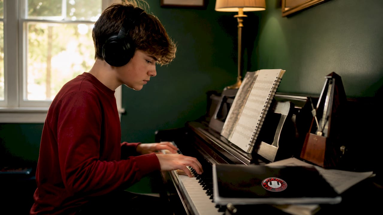 Teen boy practicing piano sight reading in classroom