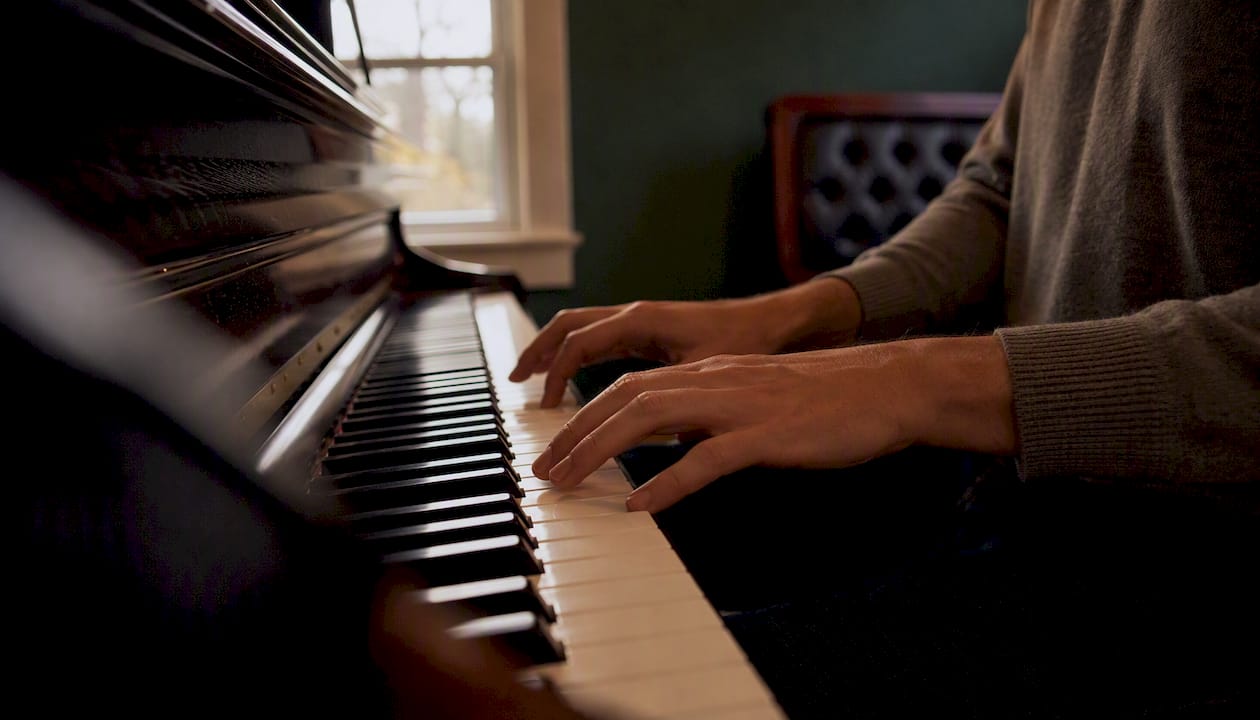 Profile view of hands playing piano with side webcam