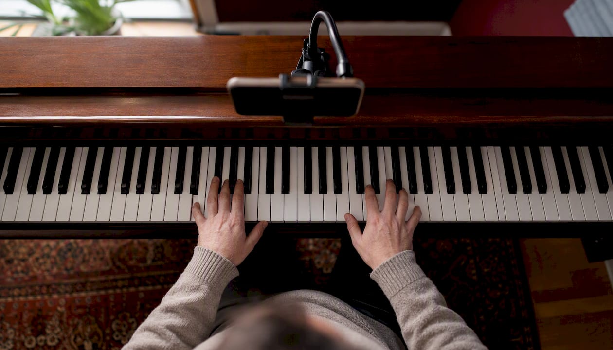 Top-down view of piano keys and fingers from mounted smartphone