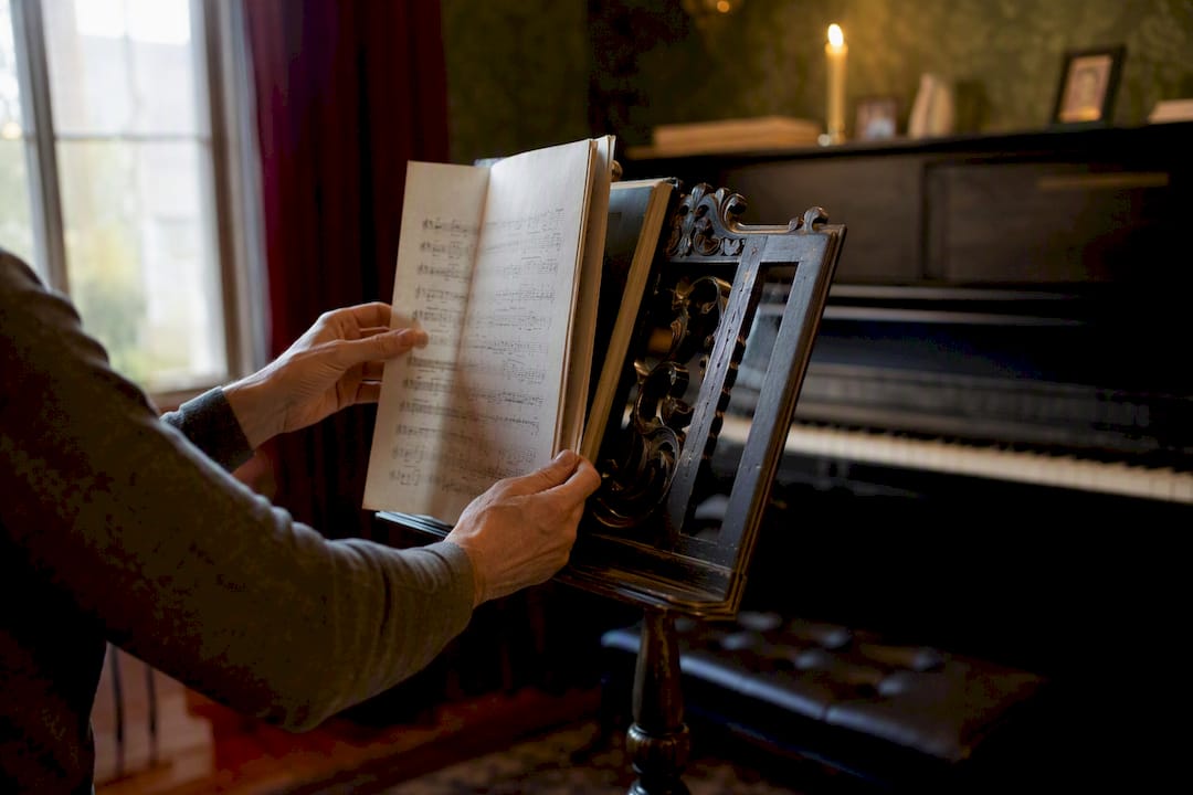 Hands selecting music sheets on stand