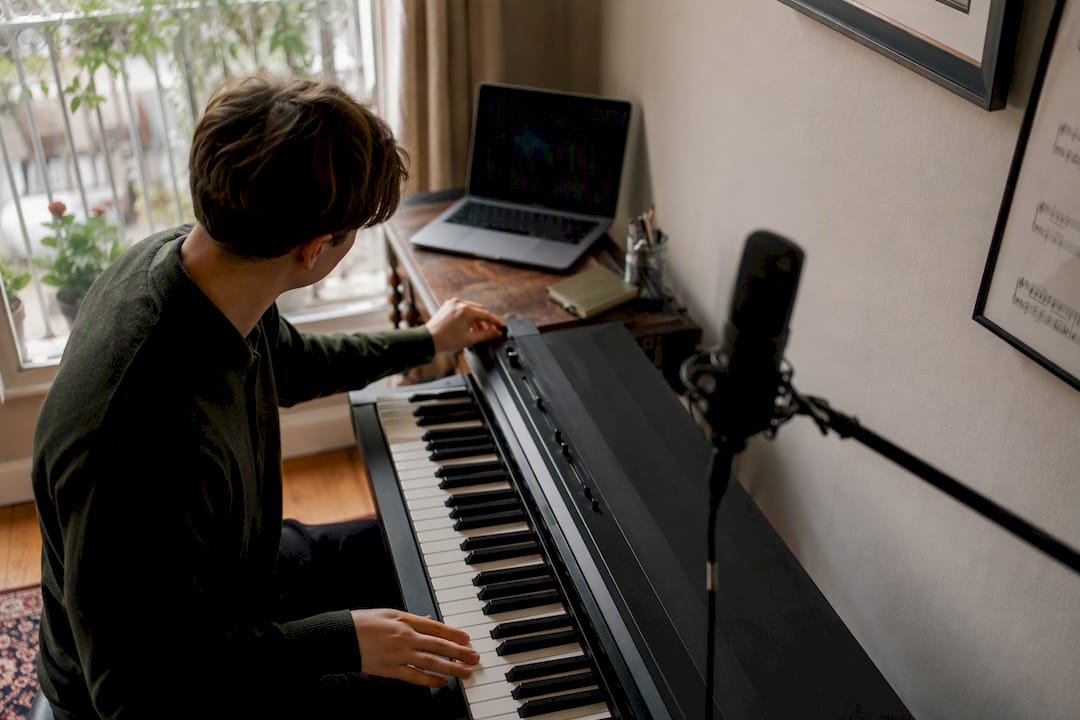 Hands setting up online piano lesson equipment