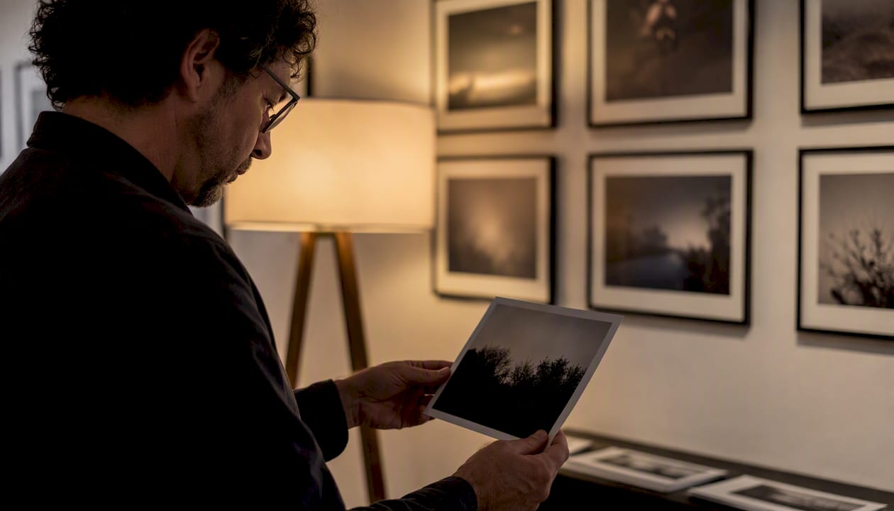 Una mano acaricia una fotografía expuesta en una galería.