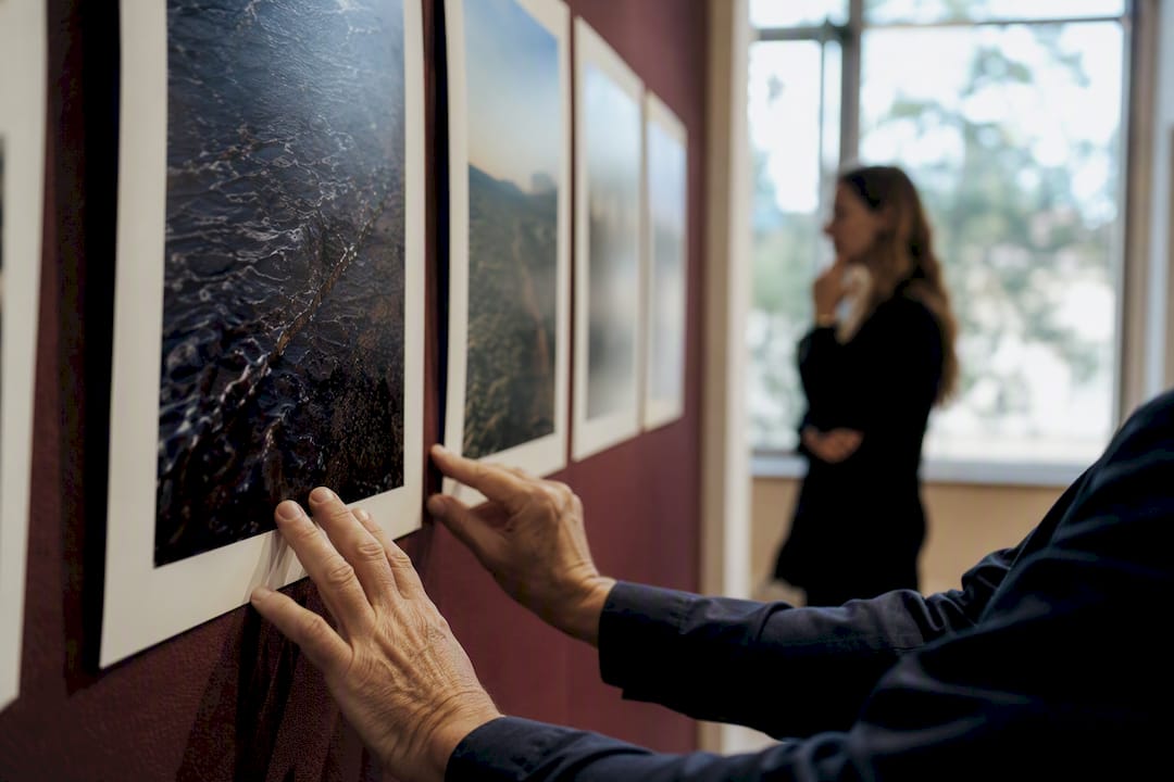 Manos revisando y analizando fotografías colocadas en la pared