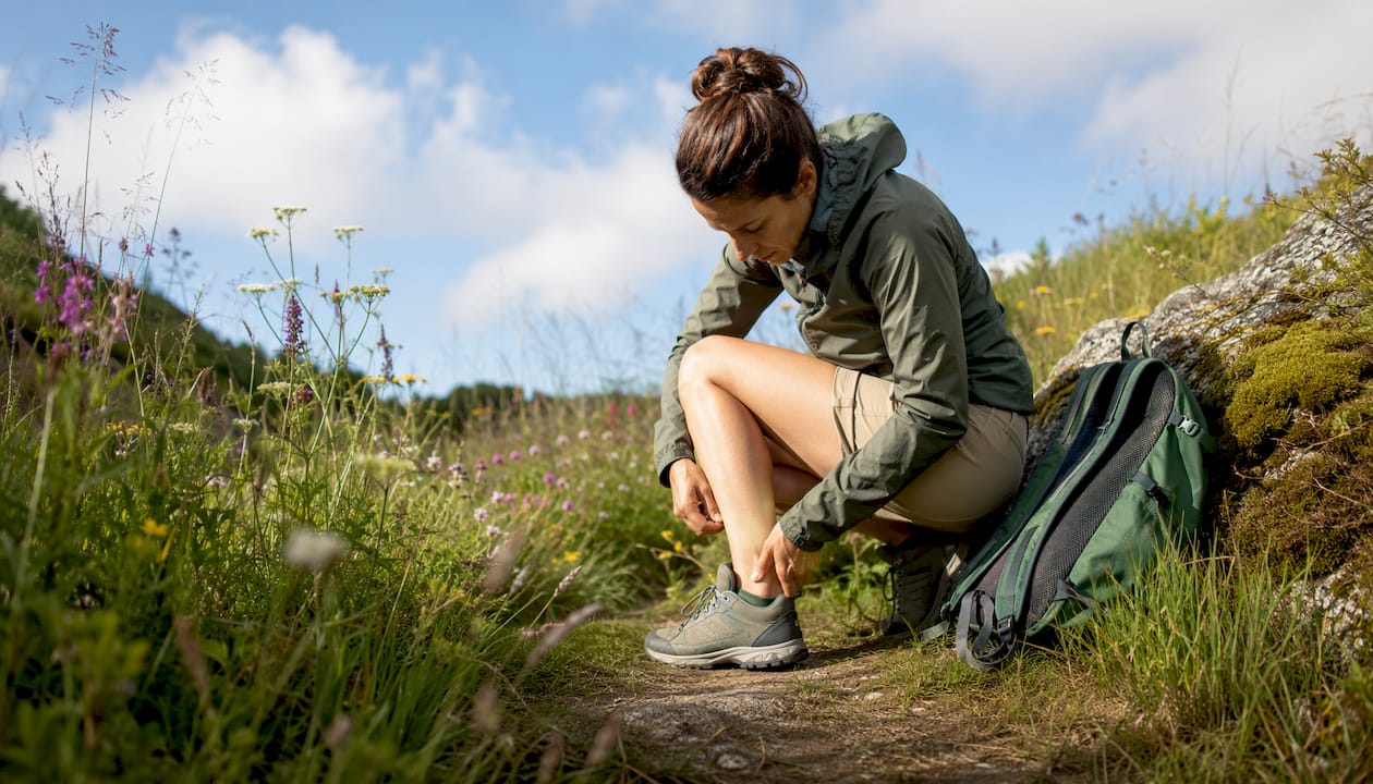 Woman walking on trail checking ankles for chiggers