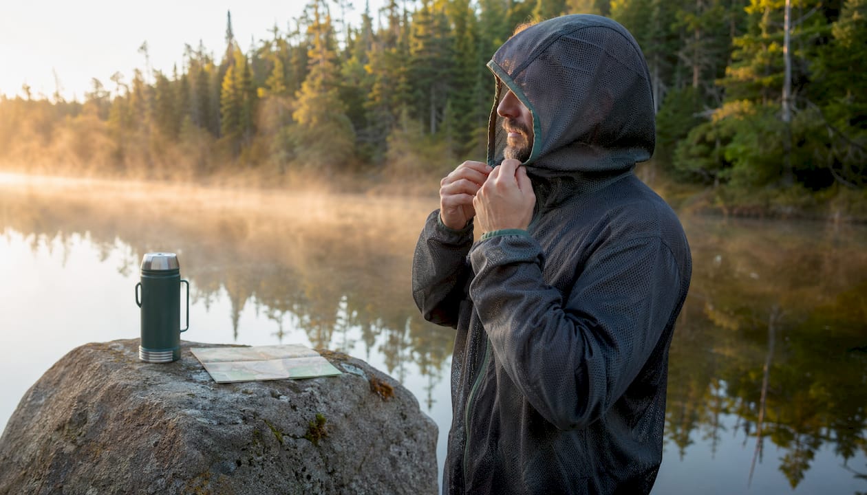 Man adjusting mesh jacket hood outdoors