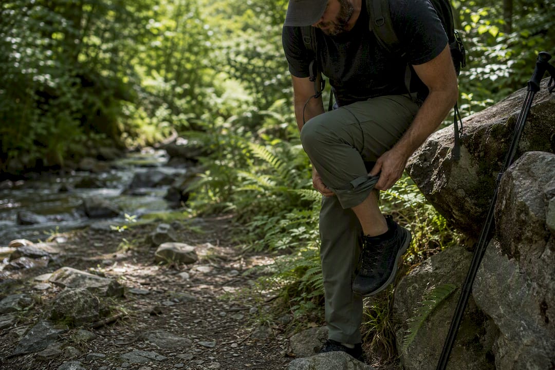 Hiker tying boot laces on forest trail