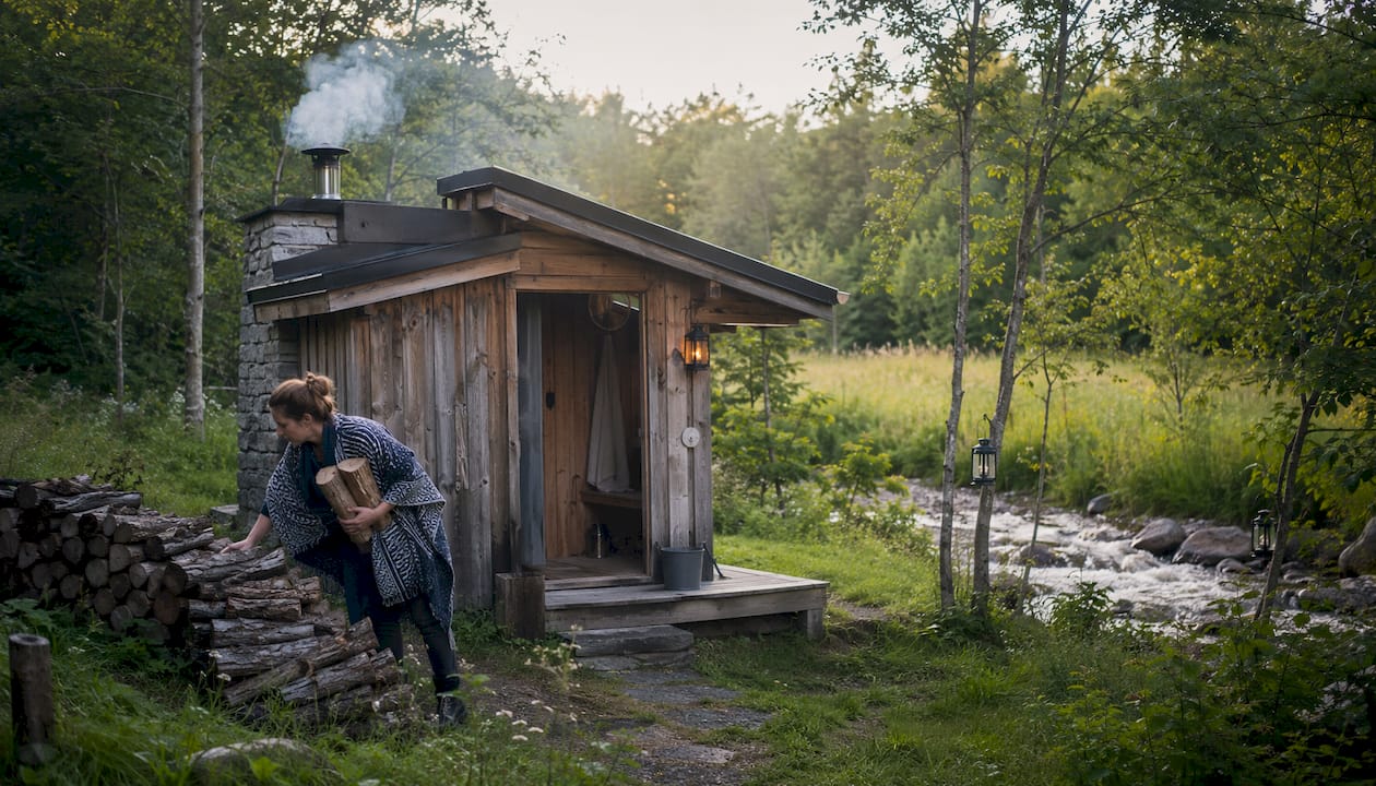 Woman stacking wood by outdoor sauna stove