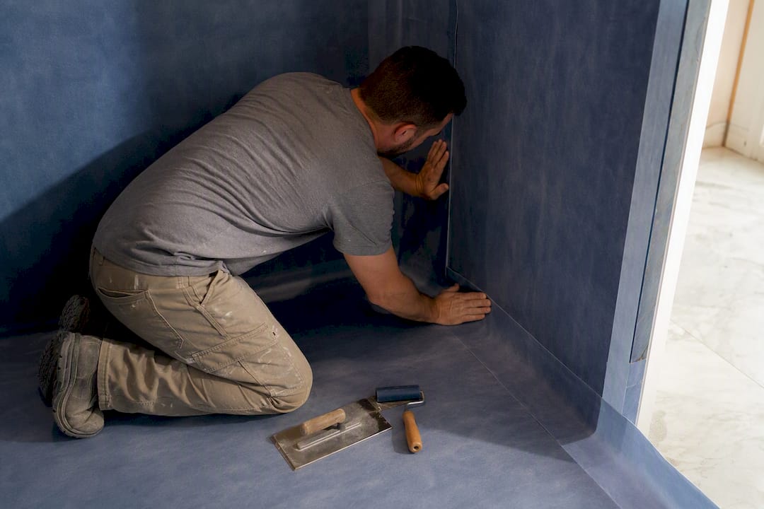 Installer applying steam room waterproofing membrane